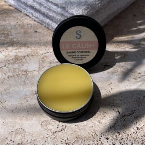 Baume jaune dans sa boite ronde noir ouverte étiquette rose