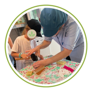 Adulte en blouse bleu aidant un enfant à tamponner son savon lors d'un atelier ludique