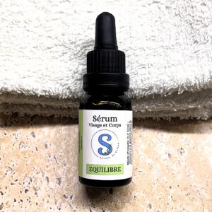 Flacon de sérum blanc et vert avec un bouchon pipette noir.