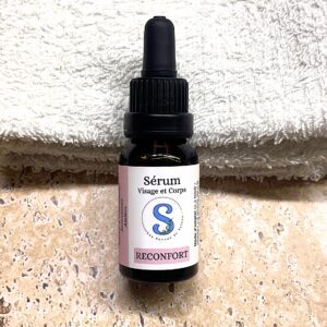 Flacon de sérum blanc er rose avec un bouchon pipette noir.